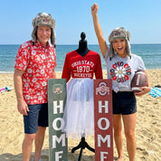 Two people on a beach with Ohio State-themed items and signs.