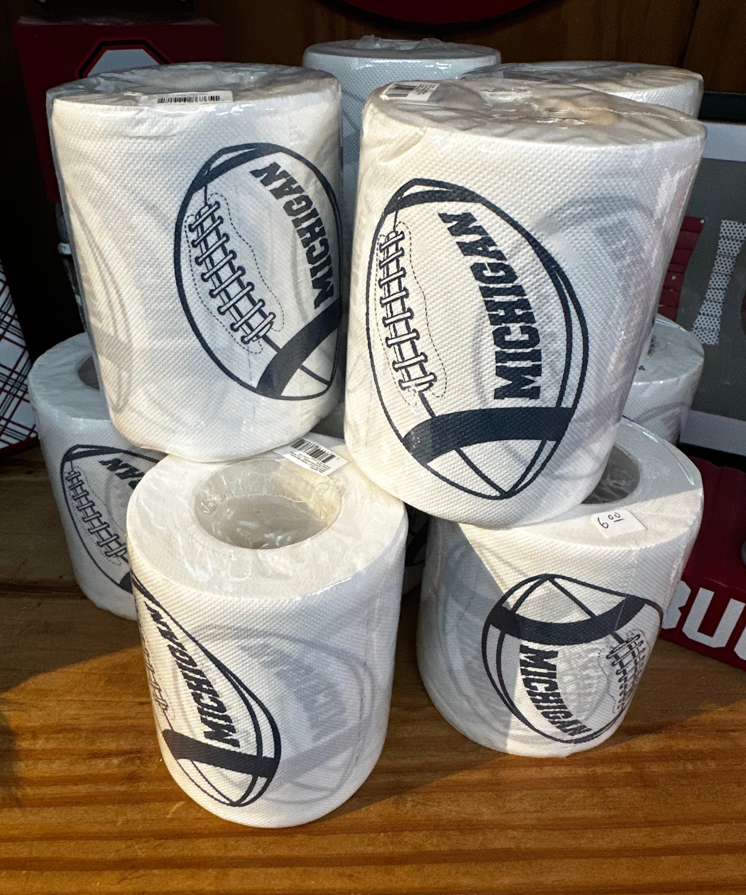 Multiple rolls of toilet paper with 'Michigan' branding on a wooden surface.