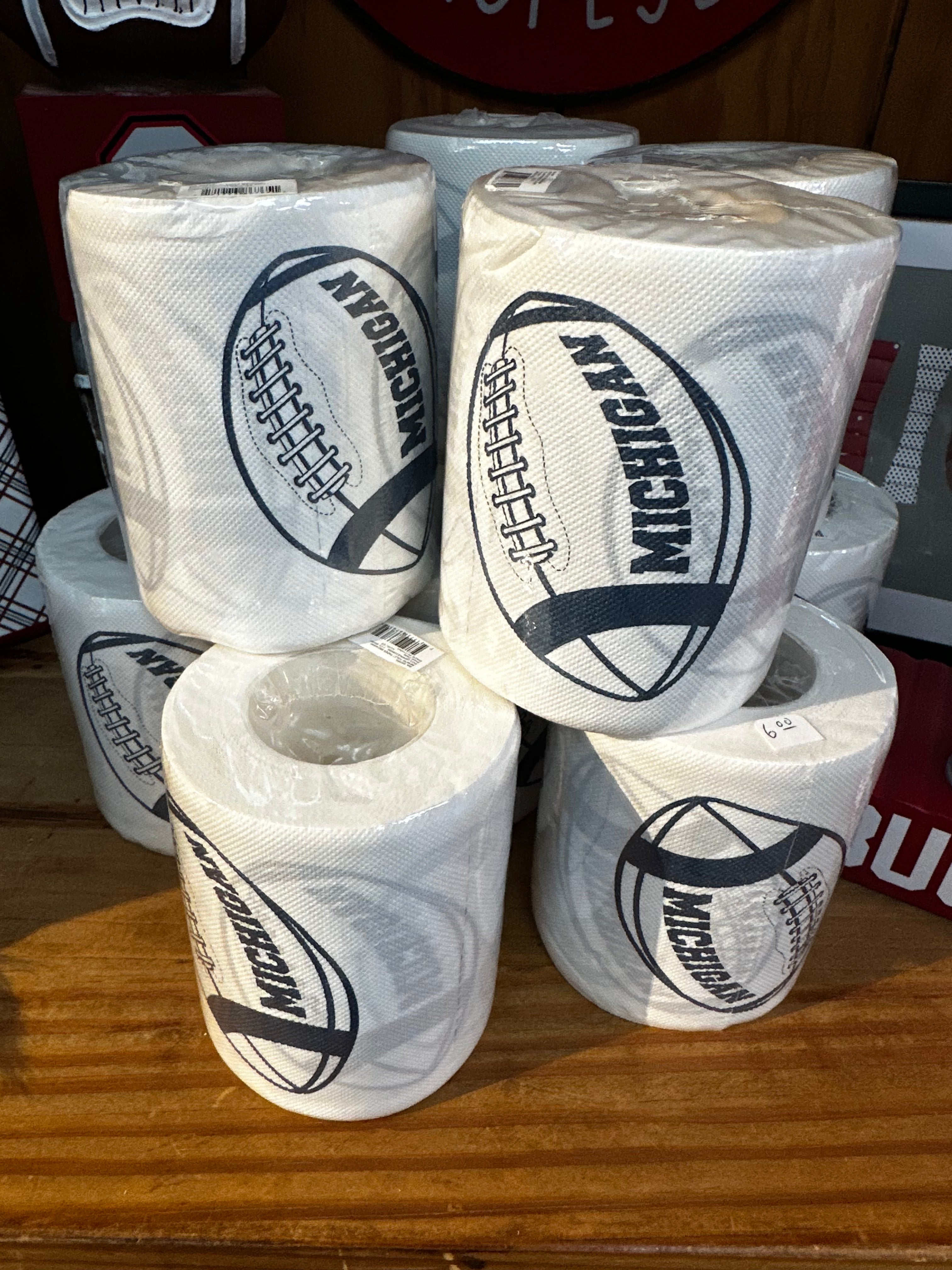 Multiple rolls of toilet paper with 'Michigan' branding on a wooden surface.
