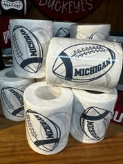 Rolls of toilet paper with Michigan logo on a wooden surface