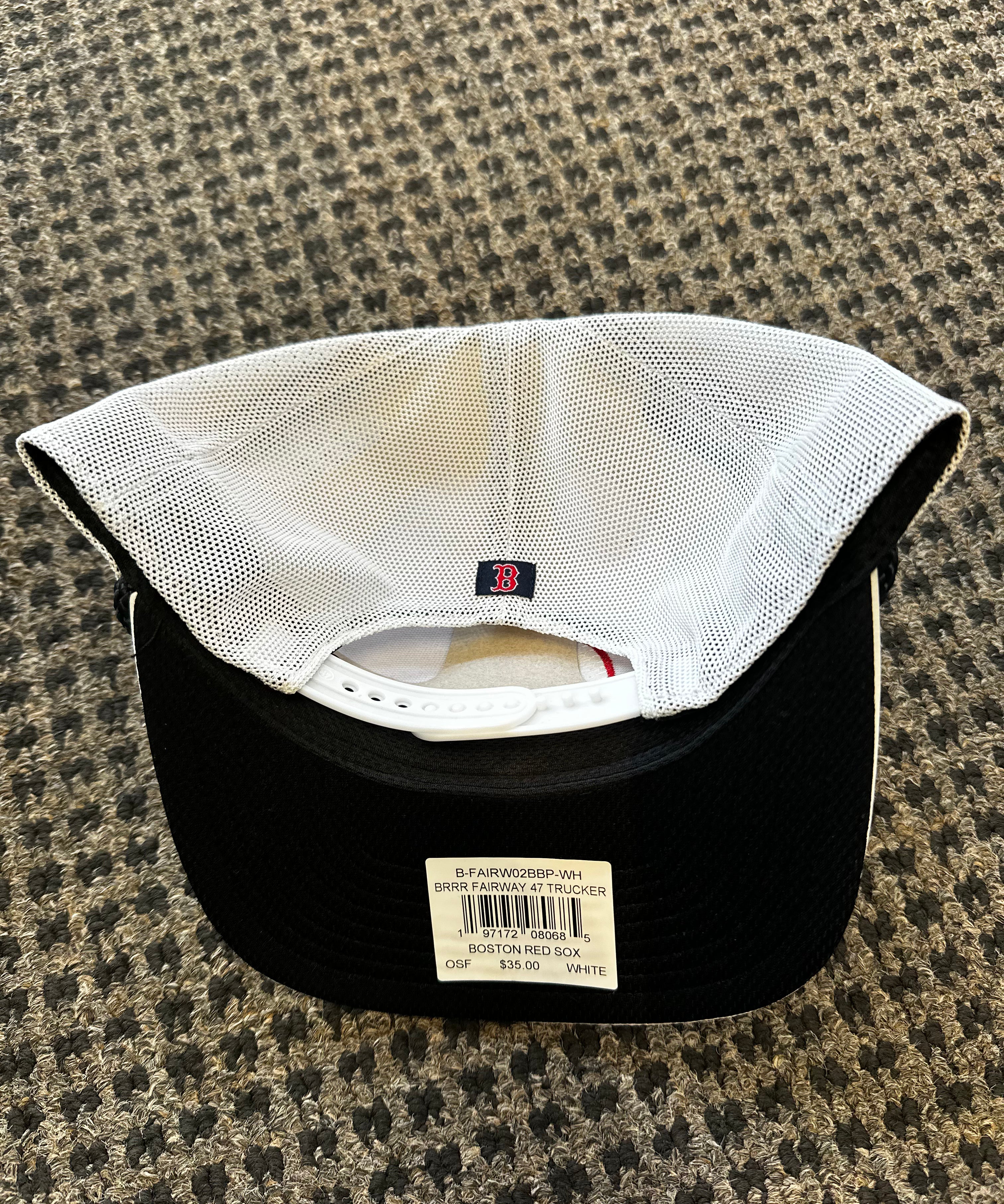 Black baseball cap with white mesh back on a textured surface