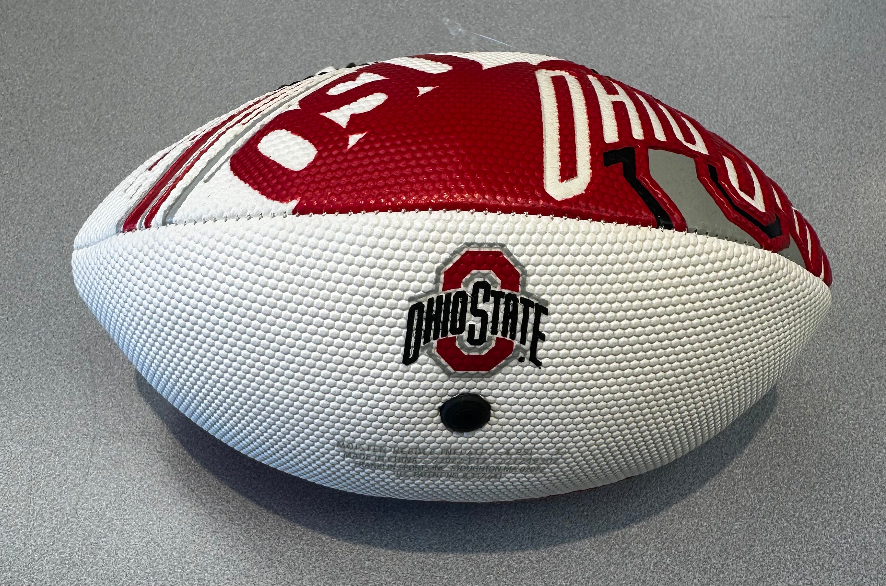 White and red football with Ohio State logo on a gray background