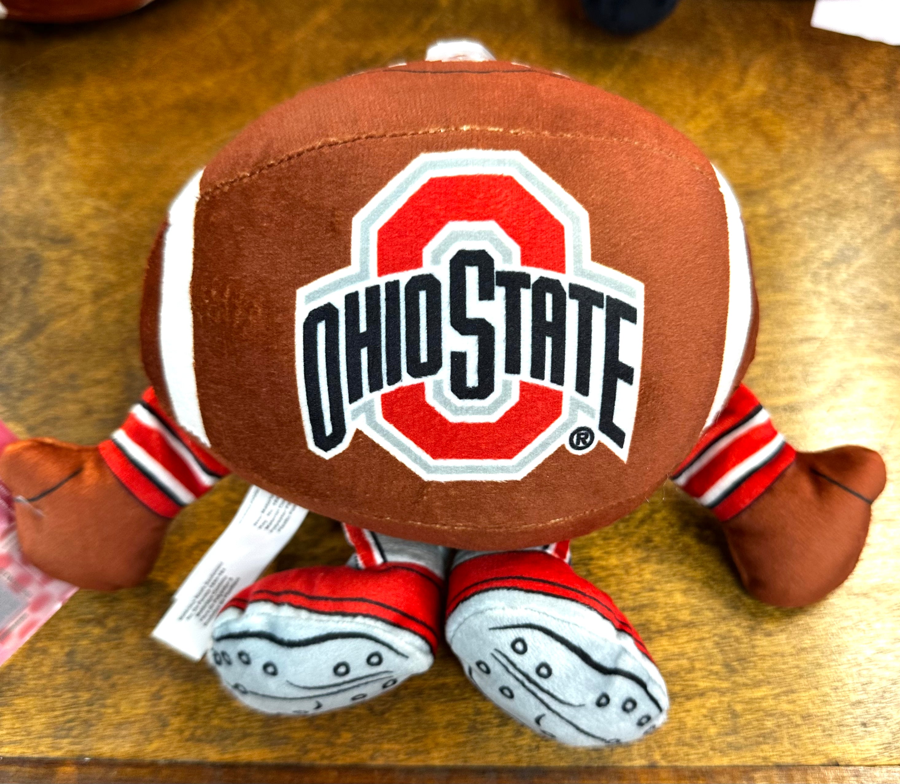 Plush toy resembling a football with Ohio State logo on a wooden surface