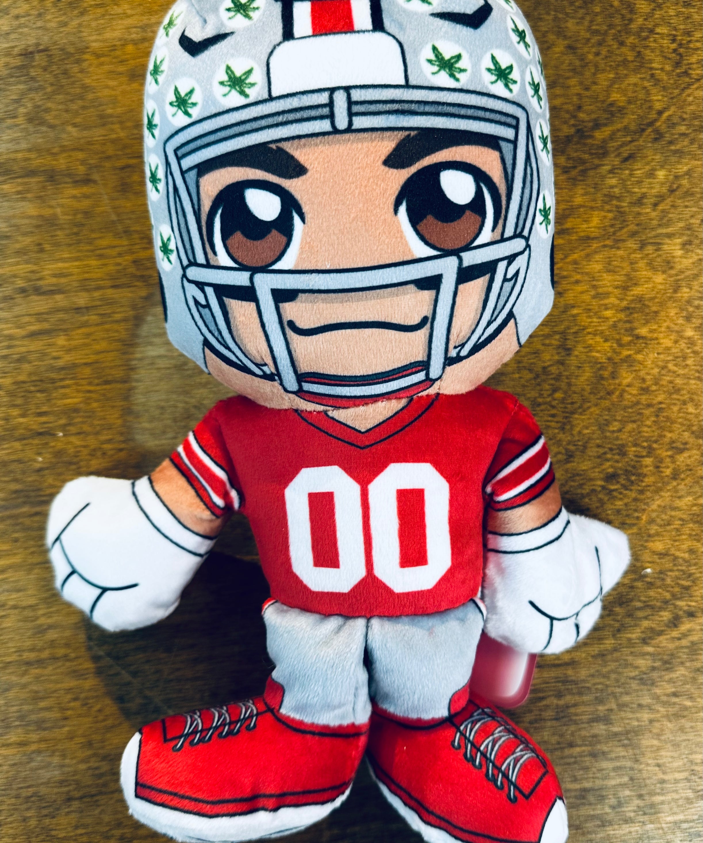 Plush toy of a football player in a helmet and uniform on a wooden surface