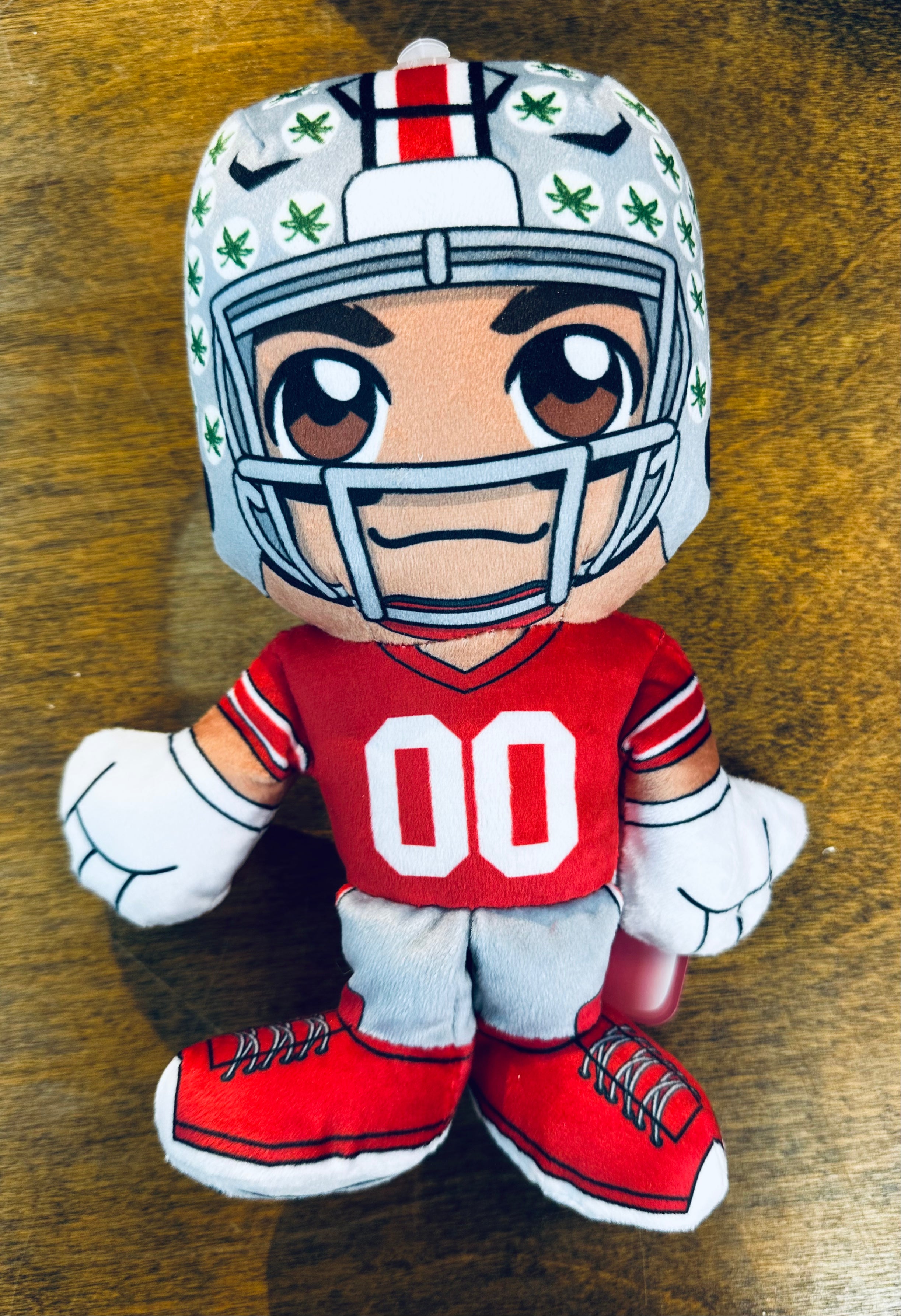 Plush toy of a football player in a helmet and uniform on a wooden surface