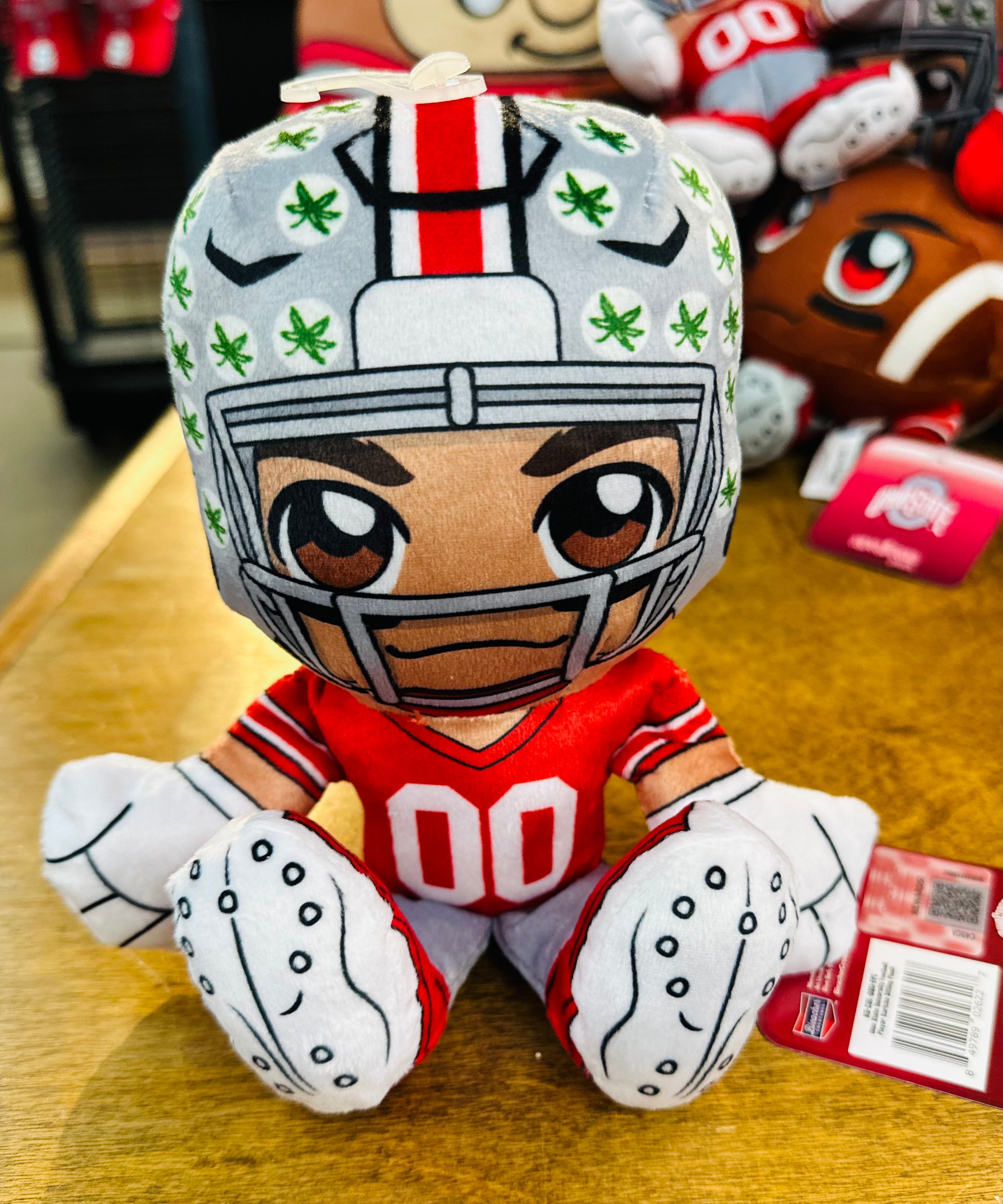 Plush toy of a football player in a helmet with green patterns on a wooden surface.