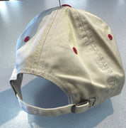 Beige cap with red accents on a reflective surface