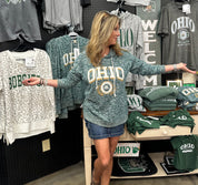 Woman wearing a green 'OHIO' sweatshirt in a store with various merchandise.