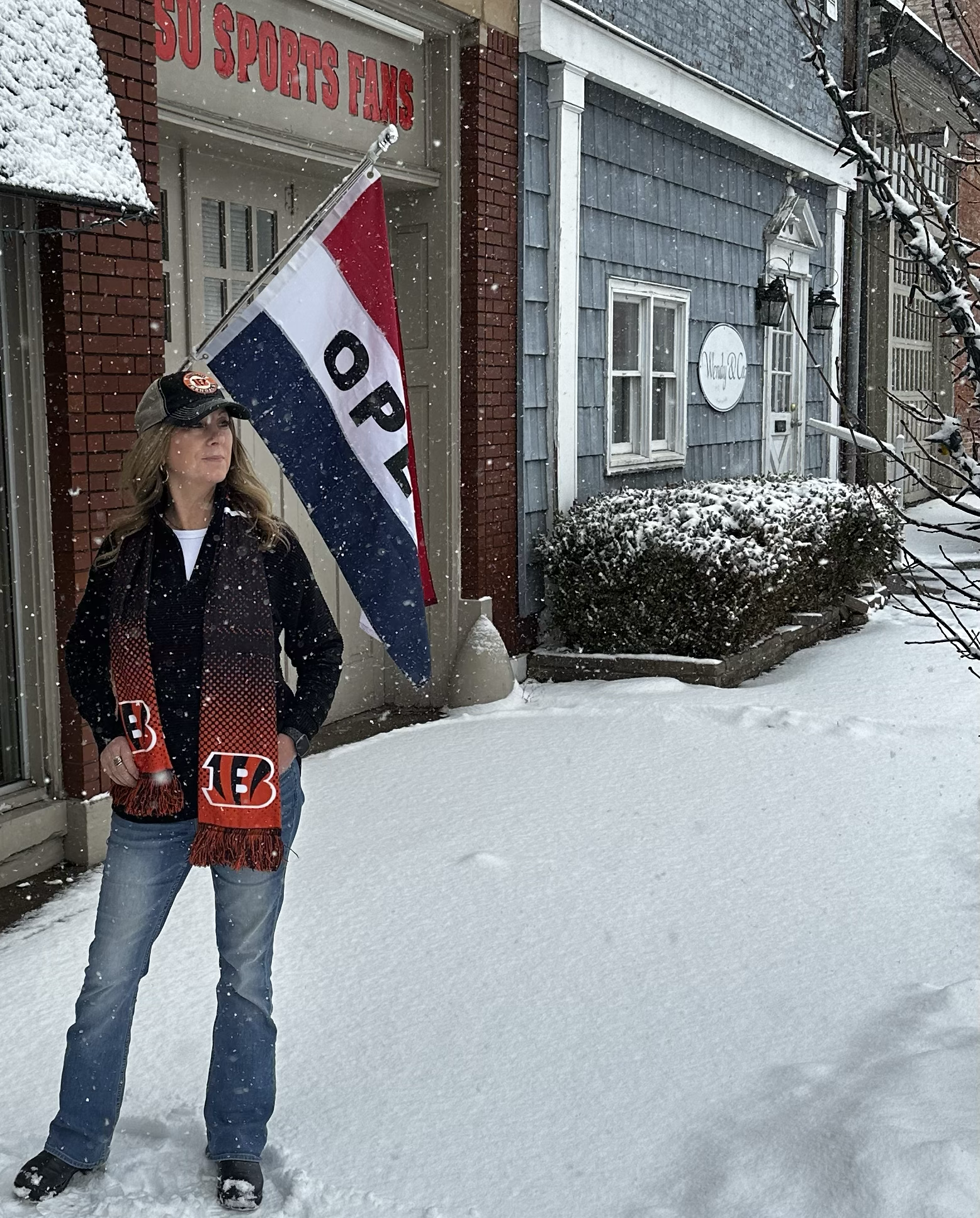 Person holding a flag with 'Open' text in front of a building with snow on the ground