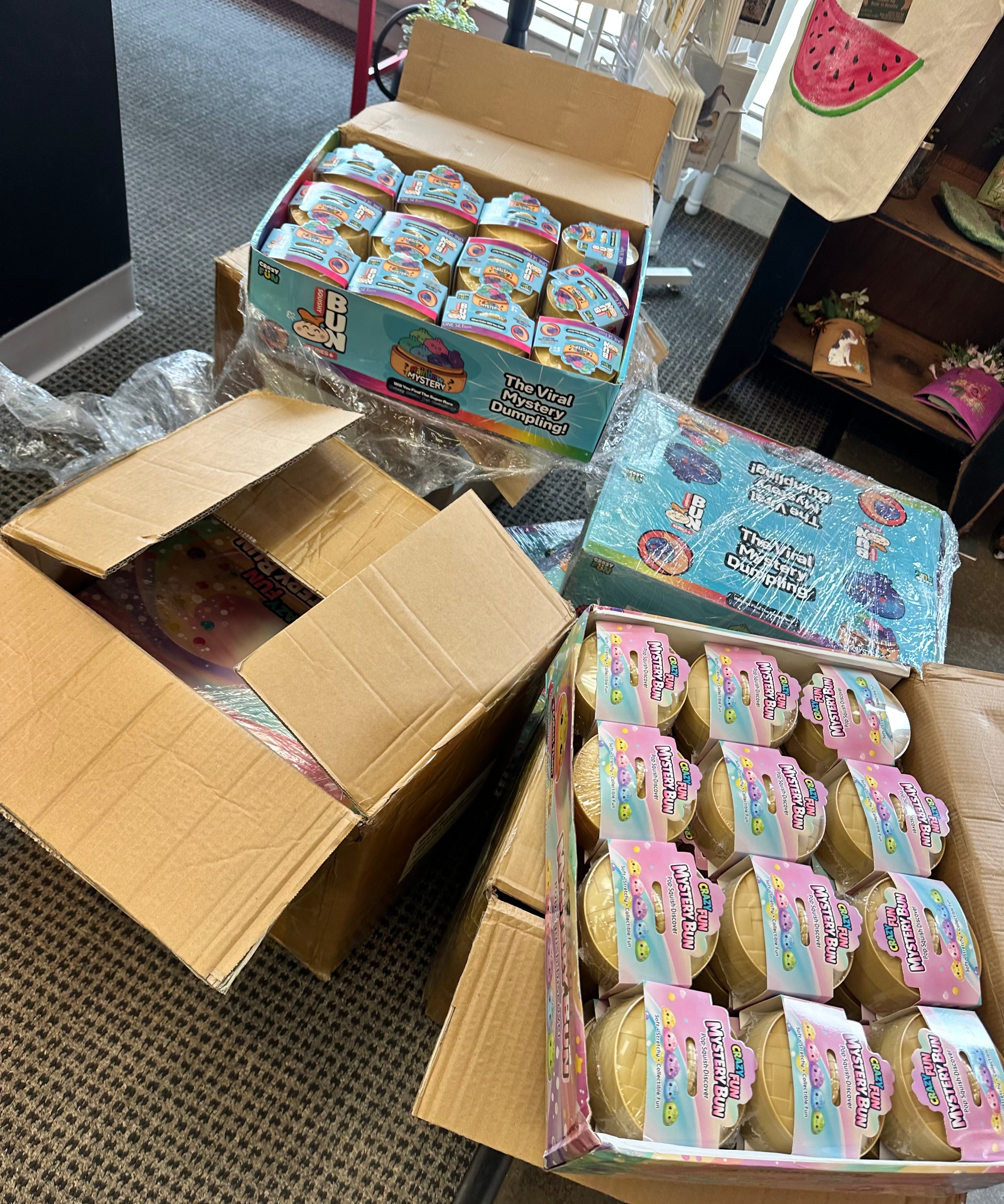 Open cardboard boxes filled with small containers on a floor.