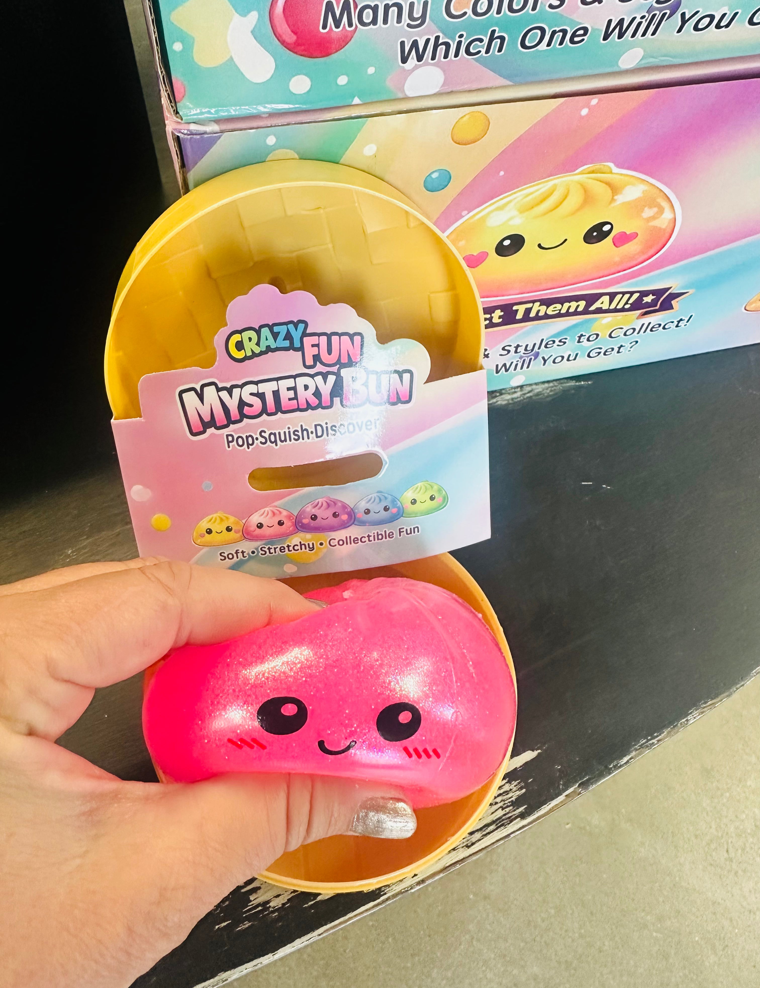 Pink squishy toy with a 'Crazy Fun Mystery Bin' packaging in front of a colorful box.