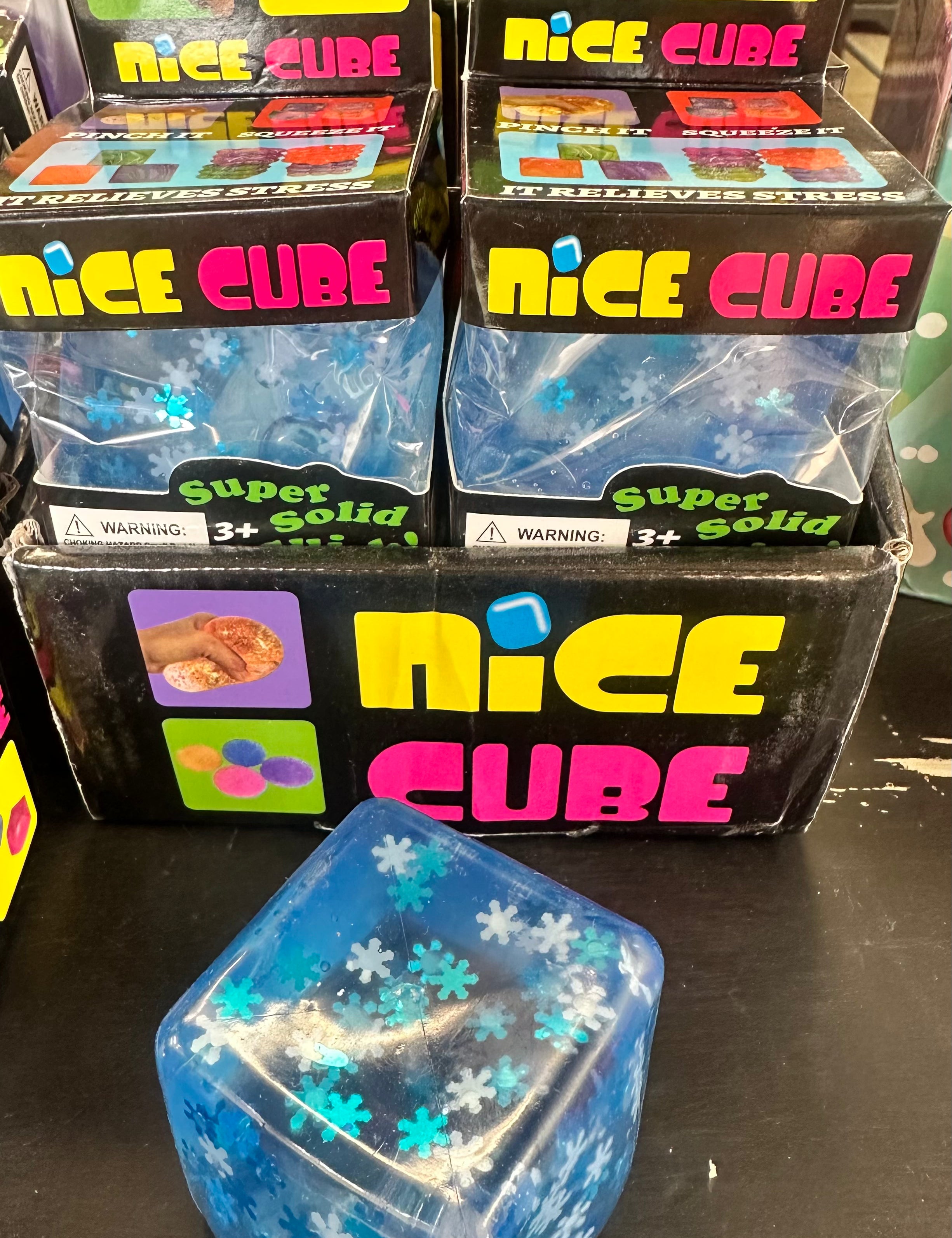 Blue 'Nice Cube' product with packaging on a black surface