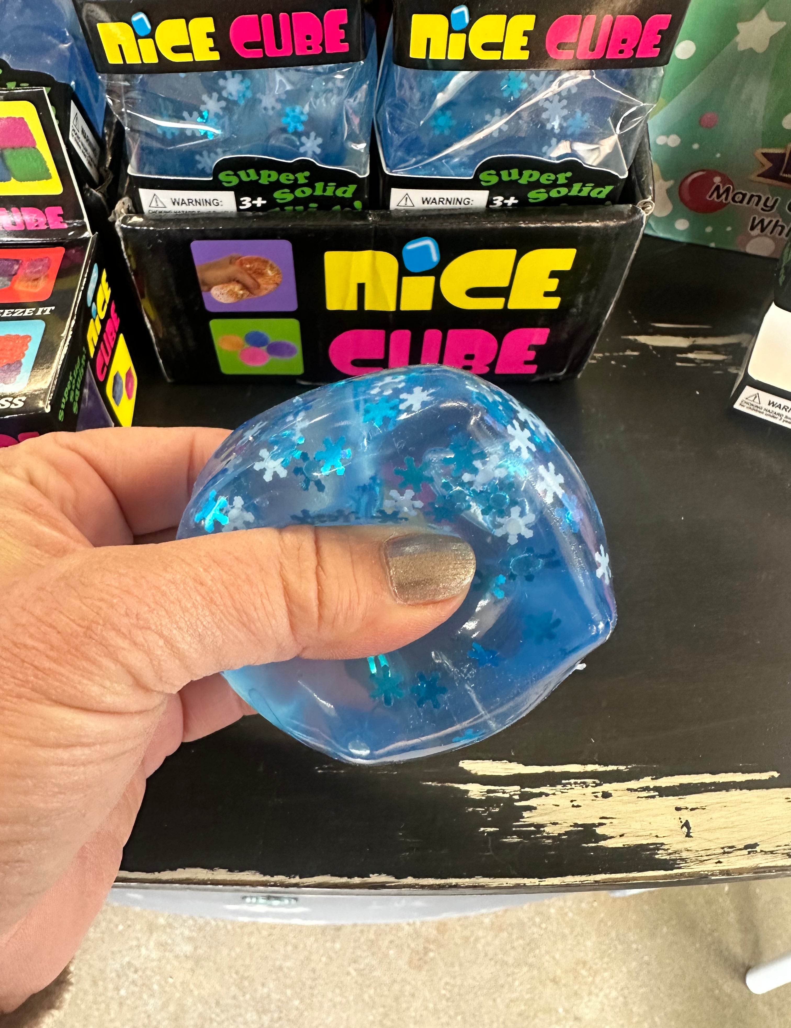 Blue glittery cube held by a hand with packaging labeled 'Nice Cube' in the background.