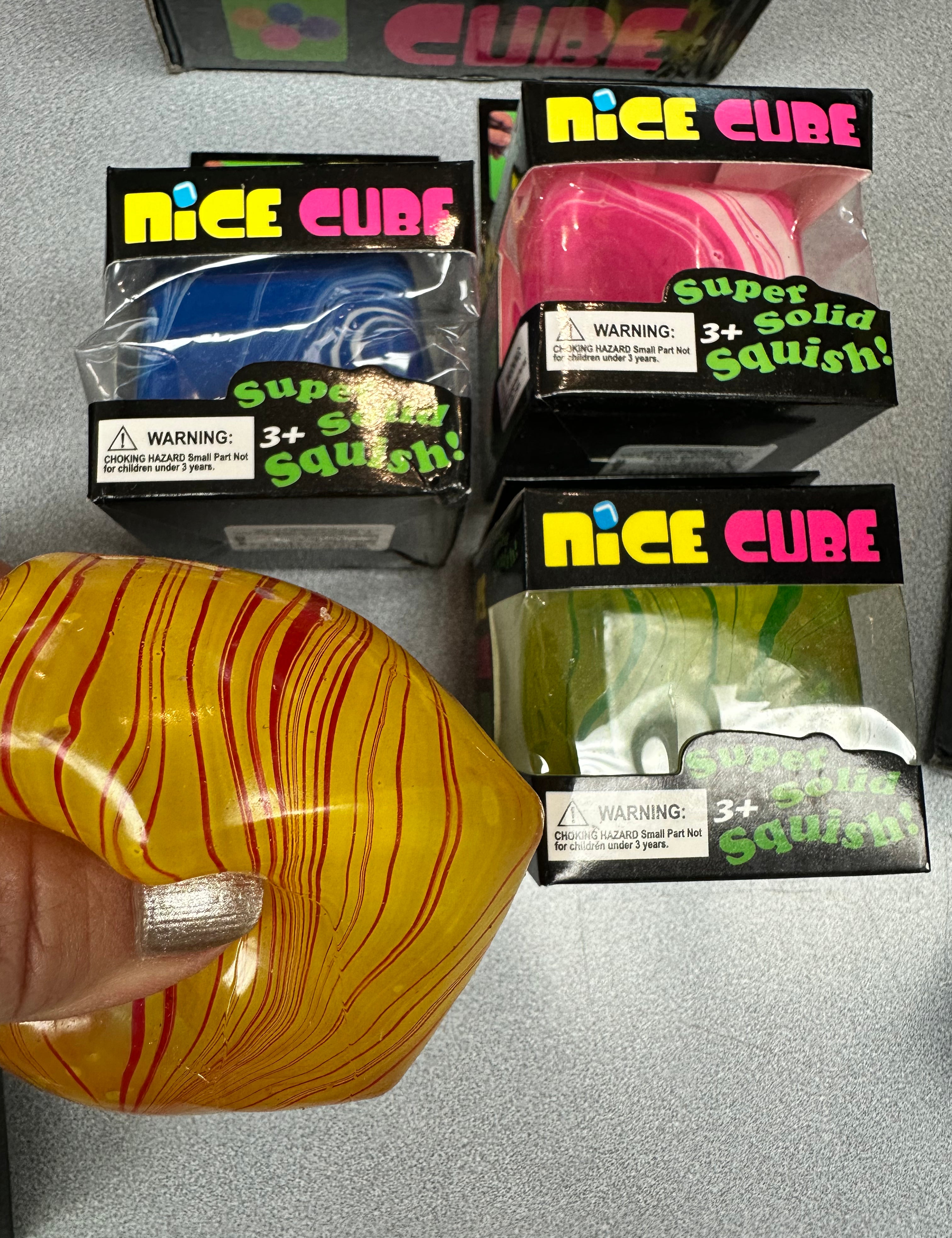 Colorful squishy cubes with packaging labeled 'Nice Cube' on a gray surface.