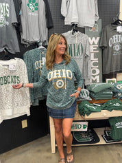 Woman wearing a 'OHIO' sweatshirt in a store with various clothing items on display.