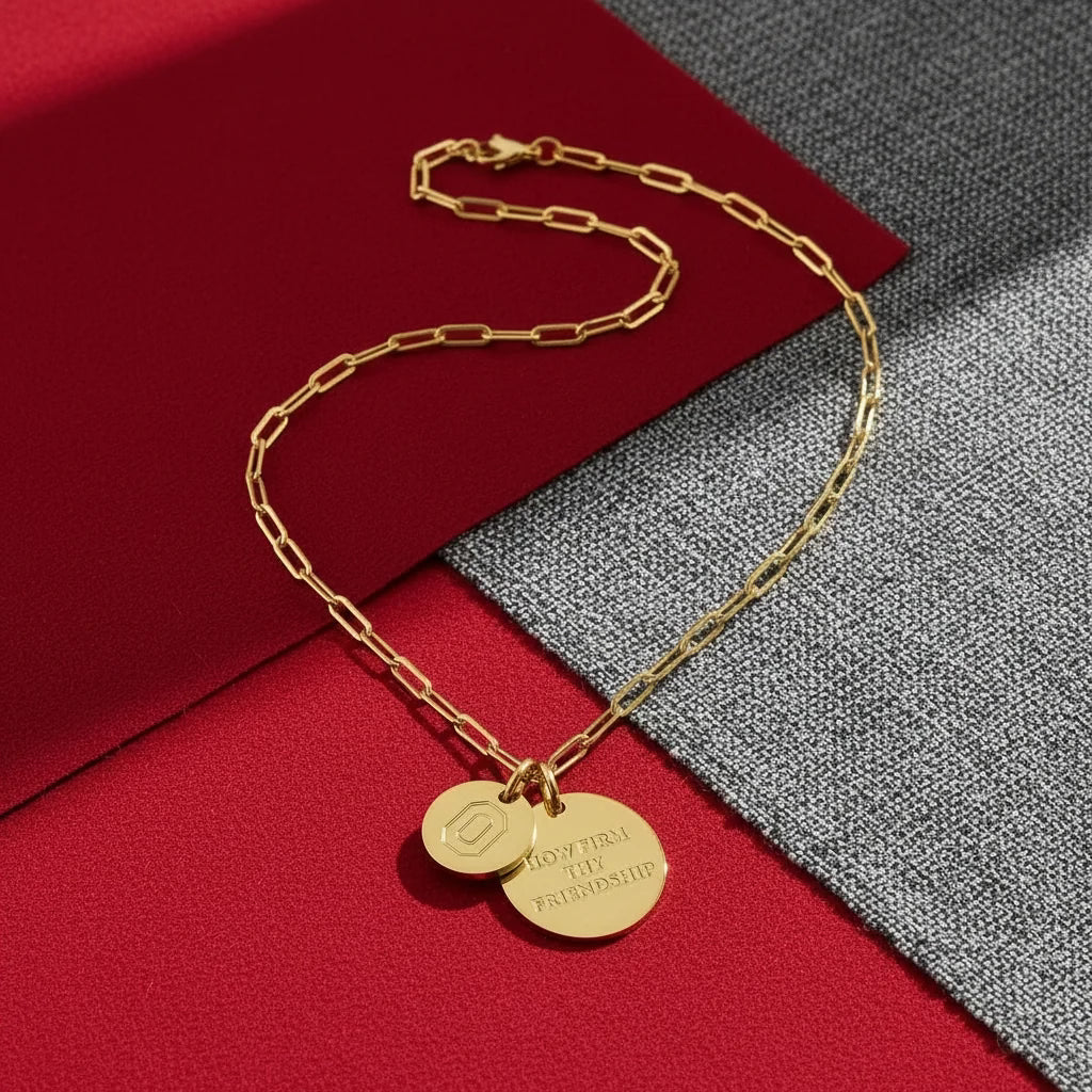 Gold chain necklace with two round pendants on a red and gray background