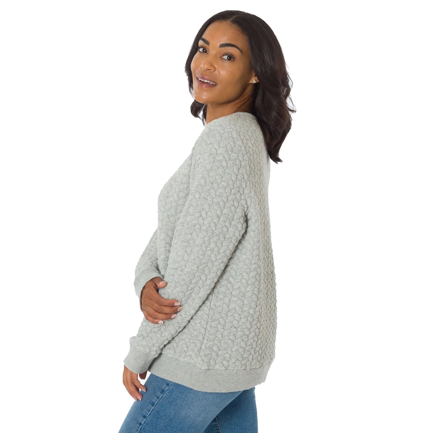 Woman wearing a textured light gray sweater on a white background