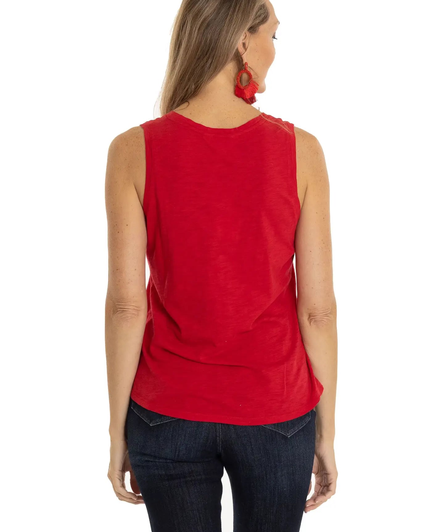 Woman wearing a red sleeveless top and dark jeans on a white background