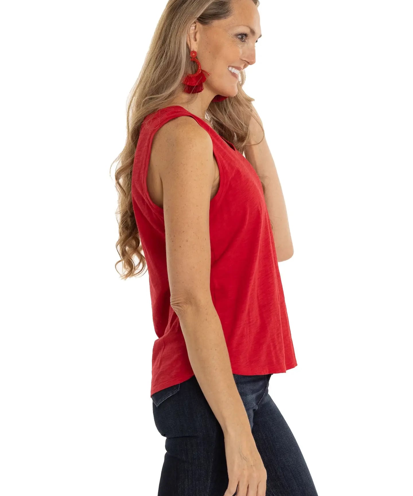Woman wearing a red sleeveless top and dark pants on a white background